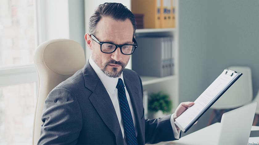 Man in glasses reviews CSDR regulation on a clipboard