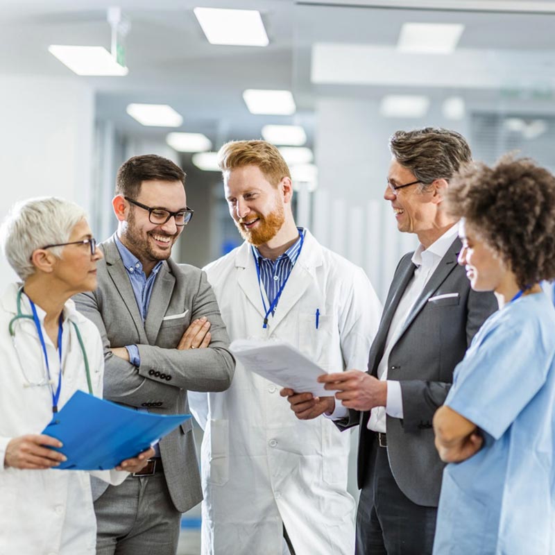 Group of five healthcare professionals standing and talking about revenue cycle management healthcare